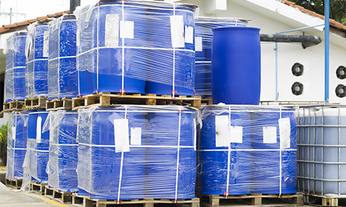 Plastic drums stacked on pallets with stretch wrap